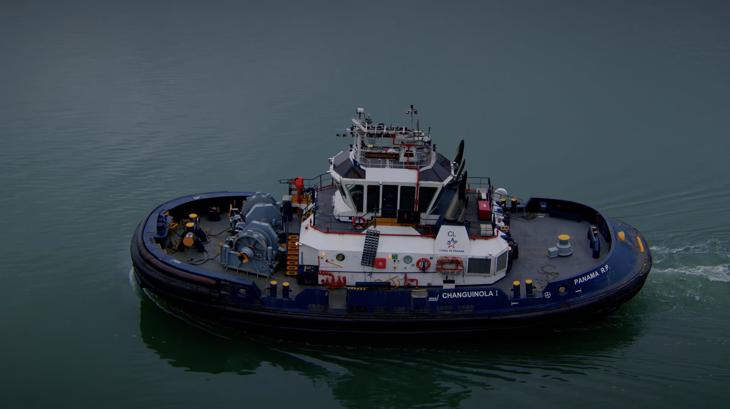 A tugboat seen from above on blue water.