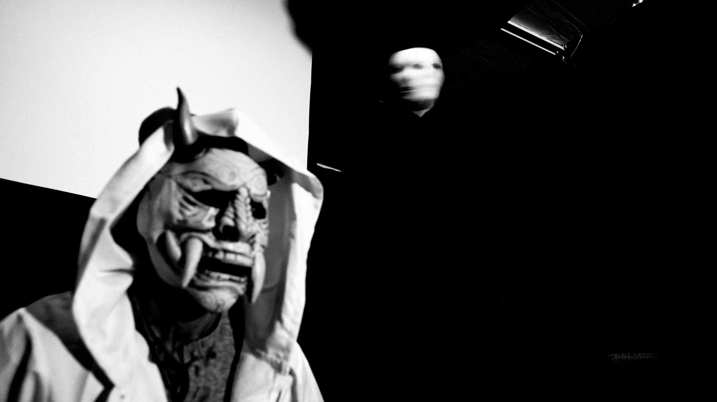 A horned theatrical mask in a monochrome film frame.