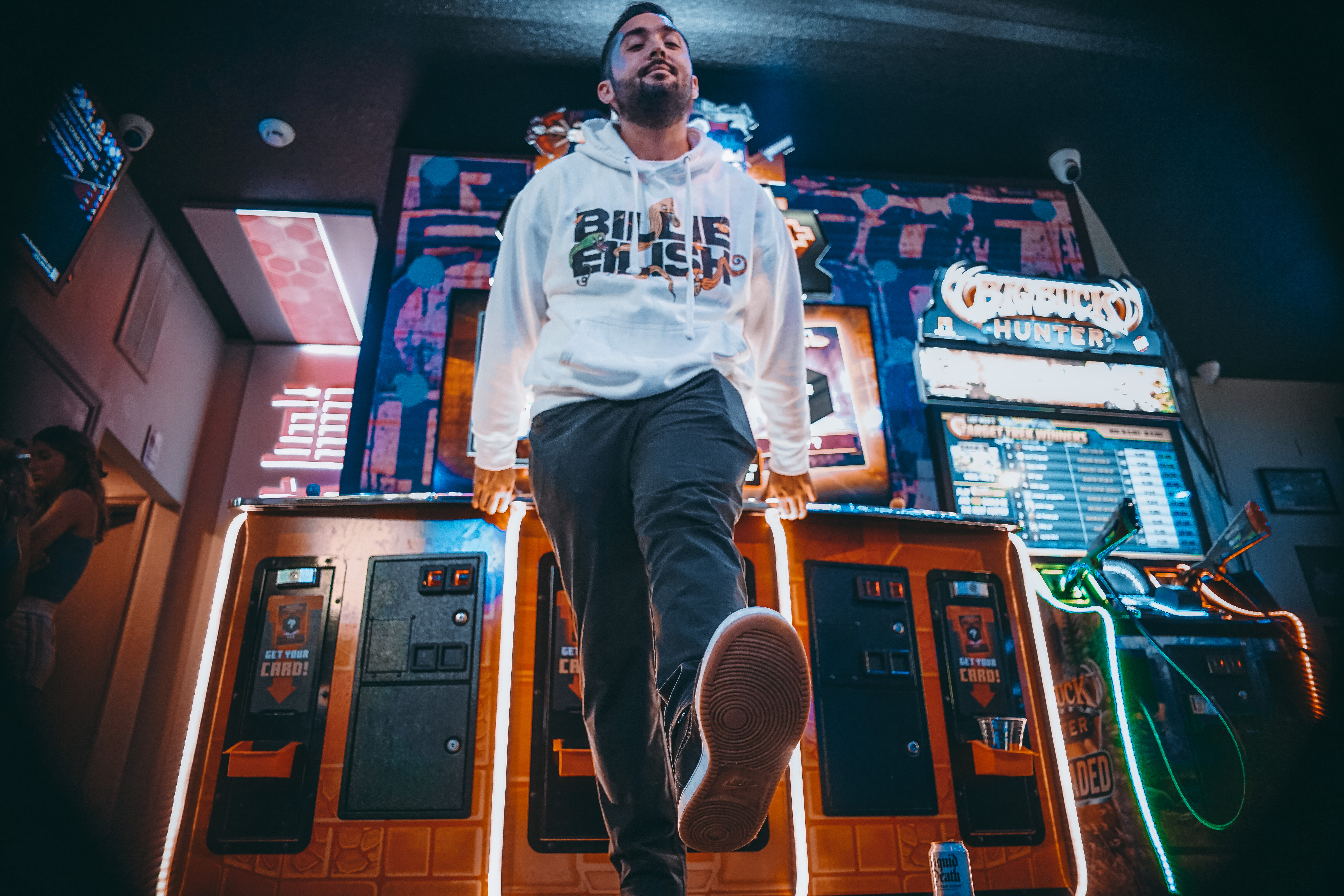 Ryan in a white hoodie, photographed from below in an arcade.