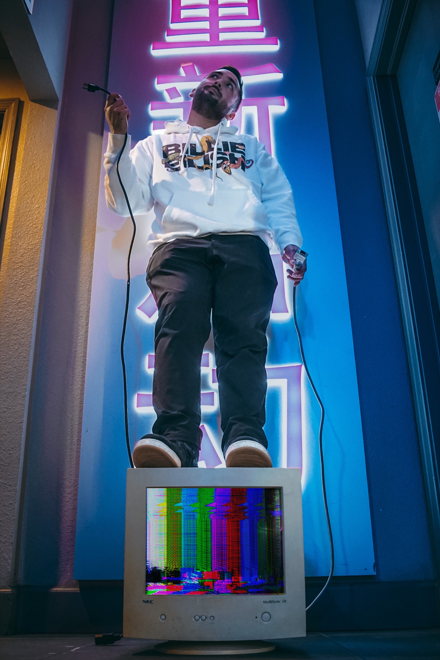 Ryan Chang standing above a monitor in neon light.