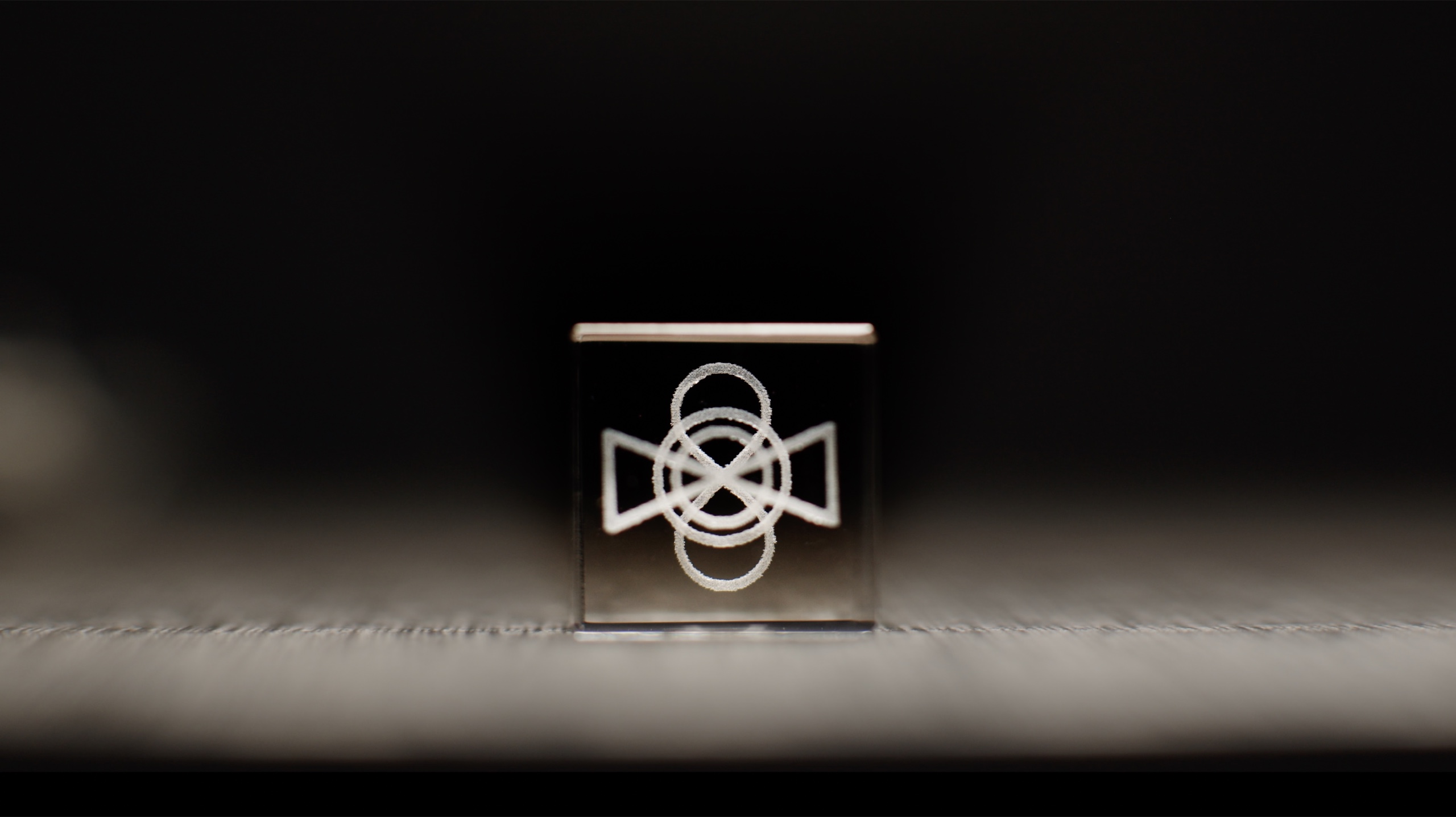 A white geometric symbol on a glass cube in shallow focus.